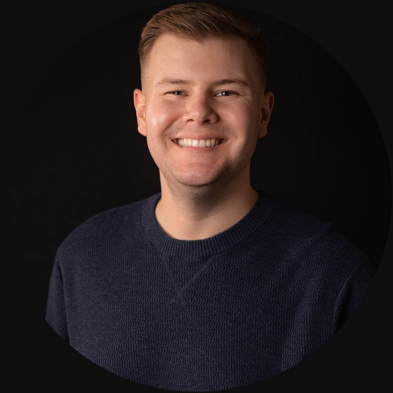 Vinney Dawson, smiling, in a navy sweater against a dark background